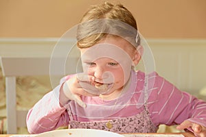 Happy girl has a snack in the kitchen. A cute small girl eats chocolate cream spred on bread. A small girl with