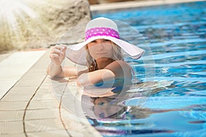 happy girl in a hat by the pool on the nature of the sea shore