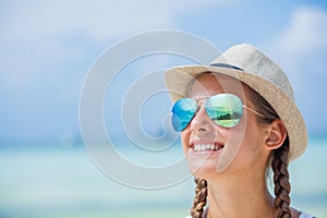 Happy girl in hat and sunglasses on beach. Summer vacation concept