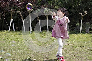 Happy girl have fun on eadow with soap bubbles toy