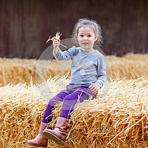 Happy girl having fun with hay on a farm