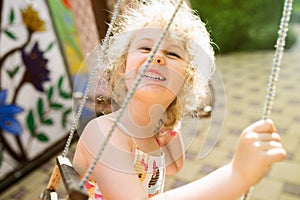 Happy girl having fun on a swing on summer day