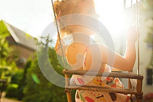 Happy girl having fun on a swing on summer day