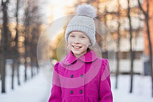 Happy girl having fun in a winter park. Winter holidays concept. Girl outdoors. Gilr wearing pink coat and knitted hat