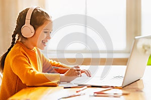 Happy girl having online lesson via laptop at home