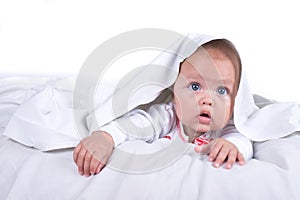 Happy Girl hiding in bed under a white blanket or coverlet. Girl at bed. Child in bed. isolated on white background