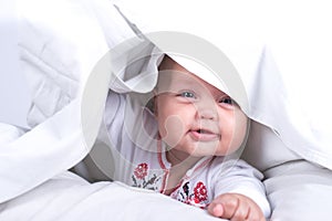 Happy Girl hiding in bed under a white blanket or coverlet. Girl at bed. Child in bed. isolated on white background