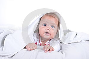 Happy Girl hiding in bed under a white blanket or coverlet. Girl at bed. Child in bed. on white background