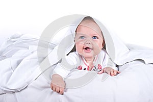 Happy Girl hiding in bed under a white blanket or coverlet. Girl at bed. Child in bed. on white background