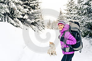 Happy girl hiking in winter forest with dog