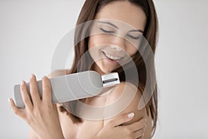 Happy girl holding bottle of shampoo or shower gel