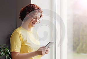 Happy girl holding cell phone using smartphone device at home. Smiling woman blogger subscribing new social media, buying in photo