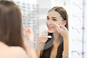Happy girl holding contact eye lenses and container