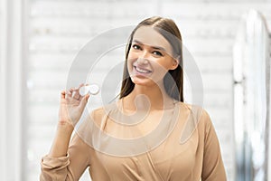 Happy girl holding contact eye lenses container