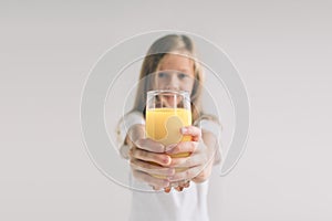 Happy girl holding glass of orange juice isolated on white background. Nerd is wearing glasses