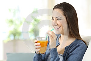 Happy girl holding an orange juice glass at home