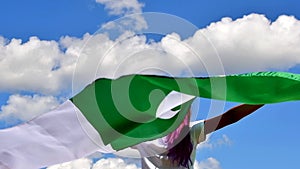 Happy girl holding Pakistan flag dancing outdoor under sunny sky.