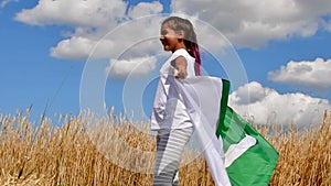 Happy girl holding Pakistan flag dancing outdoor under sunny sky.