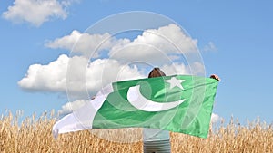 Happy girl holding Pakistan flag dancing outdoor under sunny sky. Smiling free proud independent patriotic Afro