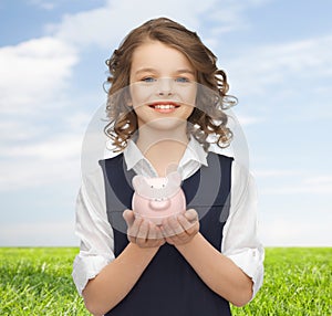 Happy girl holding piggy bank on palms