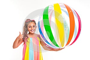 Happy girl holding a striped bright inflatable swimming ball and shows a class on a white background