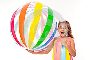 Happy girl holding a striped bright inflatable swimming ball on a white background