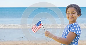 Happy girl holding a USA flag in the beach