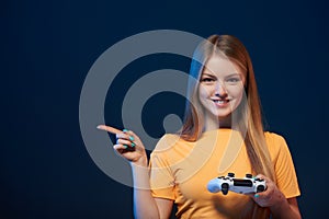 Happy girl holding video game joystick pointing finger to side