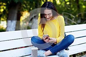 A happy girl holds in hands the smartphone during buying on sales. A young woman has joyful expression during conversation online