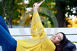 Happy girl holds in hands the smartphone taking self-portrait. Young woman has joyful expression during conversation online with