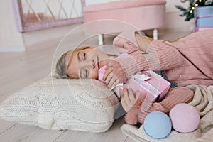 Happy girl hugging a Christmas gift box. kid lying on a pillow and holding a present