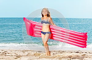 Happy girl with inflatable mattress on white beach