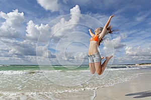 Happy girl jumping on the beach on holidays