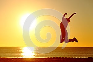 Happy girl jumping on the beach at sunset