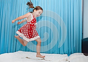 Happy girl jumping on the bed