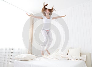 Happy girl jumping and having fun in bed