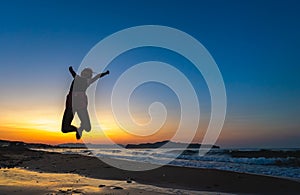 Happy girl jumping high at sunset