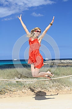 Happy girl jumping and laughing on the beach