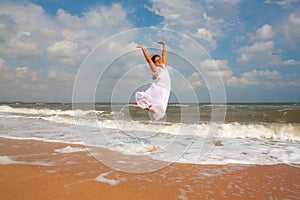 Happy girl jumping on the sunny beach