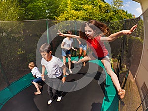 Happy girl jumping on trampoline with her friends photo