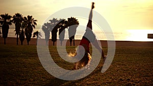 Happy girl jumps and doing cartwheels on beach enjoying sunset