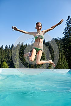 Happy girl jumps into swimming pool