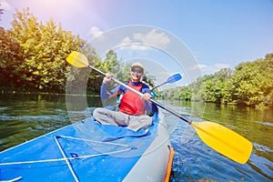 A happy girl in a Kayak. Girl Paddling in kayak on the river water at sunny summer day.