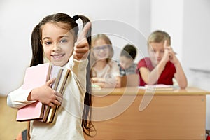 Happy girl keeping books and showing sign ok while standing