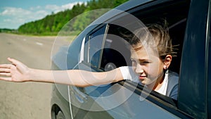 Happy girl kid child leaned out of a car window. happy family journey travel concept. The girl stuck his hands out of