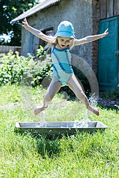 Happy girl kid jumping in the trough