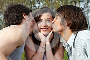 Happy girl kissed by two young boys