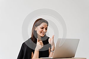 Happy girl with laptop showing thumbs up on video communication with friends. Successful business woman works remotely