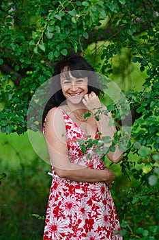Happy girl laughing against a green trees background. Concept of joy.Smiling happy woman. Happy cheerful smiling brunette woman wi