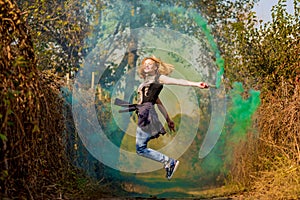 Happy girl laughing and running with green color smoke bomb in forest.